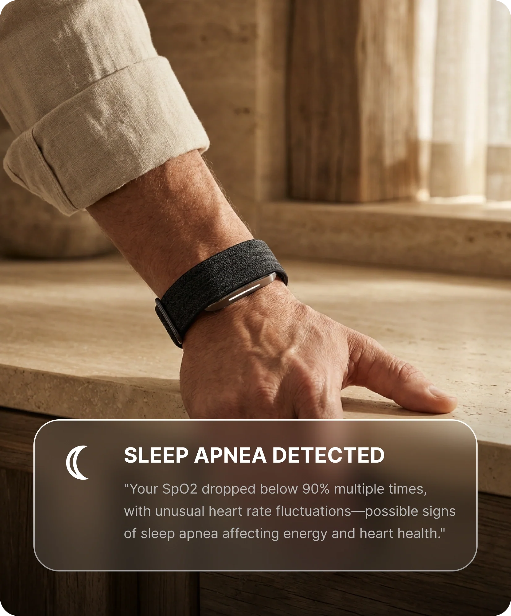 Close-up of a person wearing a hume band 2.0 while resting a hand on a countertop. An on-screen alert indicates sleep apnea detection, noting low blood oxygen levels and unusual heart rate fluctuations.