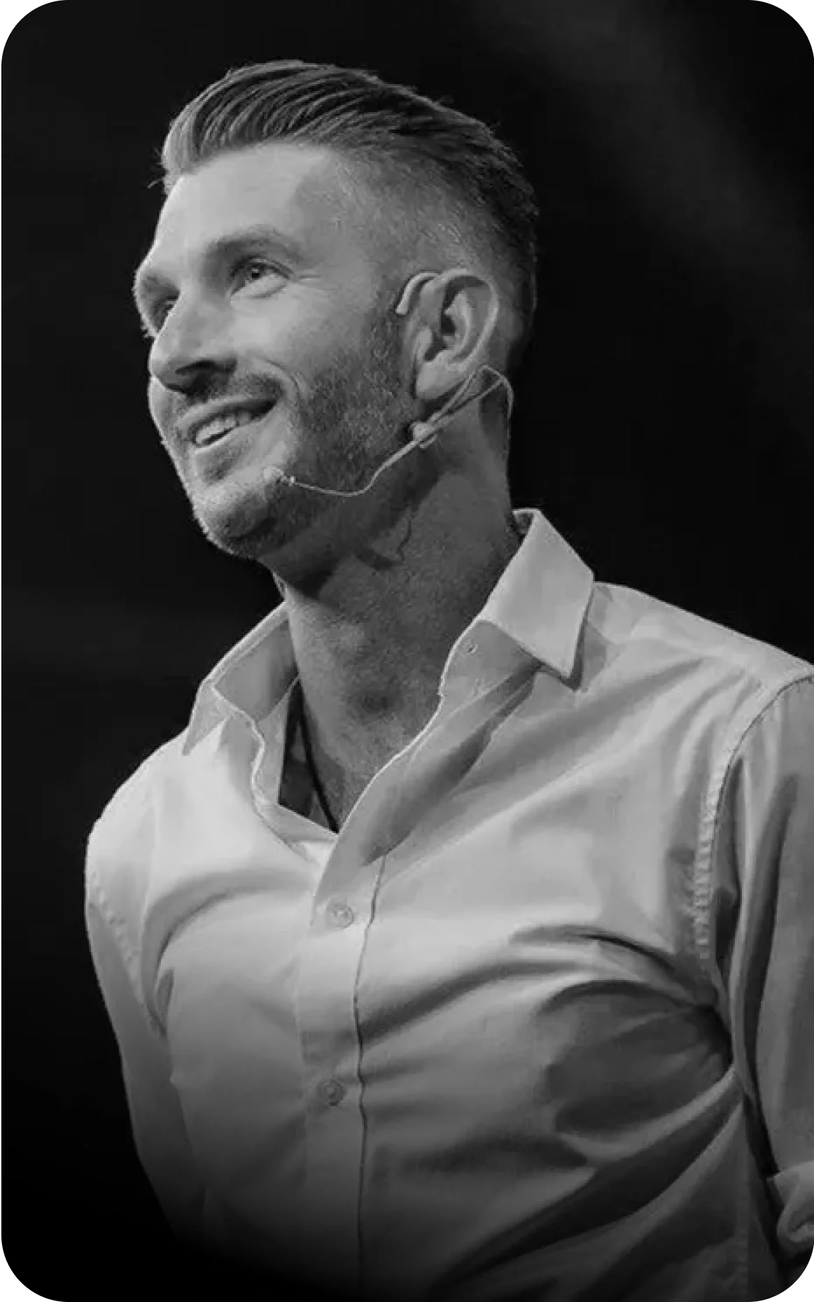 Black and white photo of a man speaking on stage with a headset microphone, labeled as Tim Bio-Hacker, Europe's Leading Biohacker.