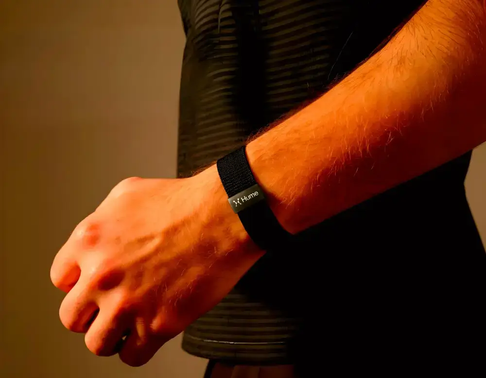 Close-up of a person wearing a Hume Band on wrist with text promoting longevity tracking, aging prevention, and powerful health data insights.